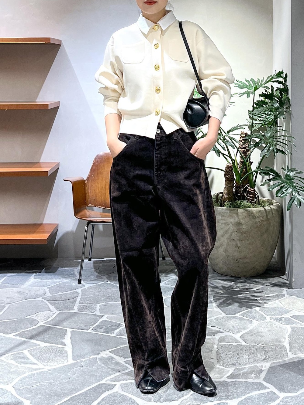 ブラック系のショルダーバッグ、ホワイト系のカーディガン/ボレロ、ブラウン系のデニムパンツを着用したレディースの冬コーディネートの1枚目の写真