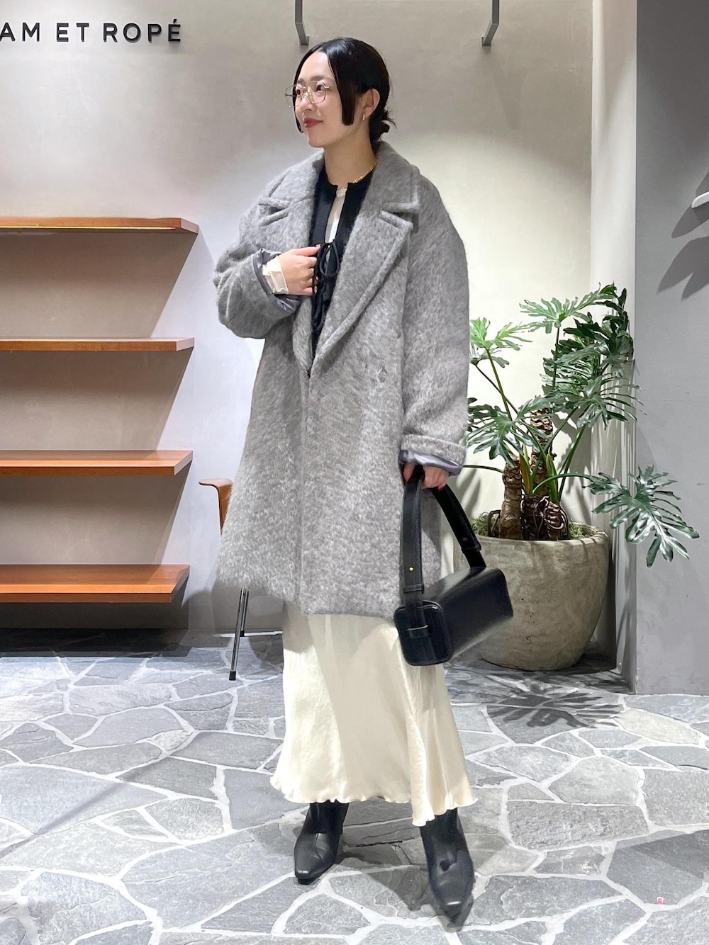 ブラック系のブーツ、ベージュ系のスカート、ブラック系のカーディガン/ボレロを着用したレディースの冬コーディネートの1枚目の写真