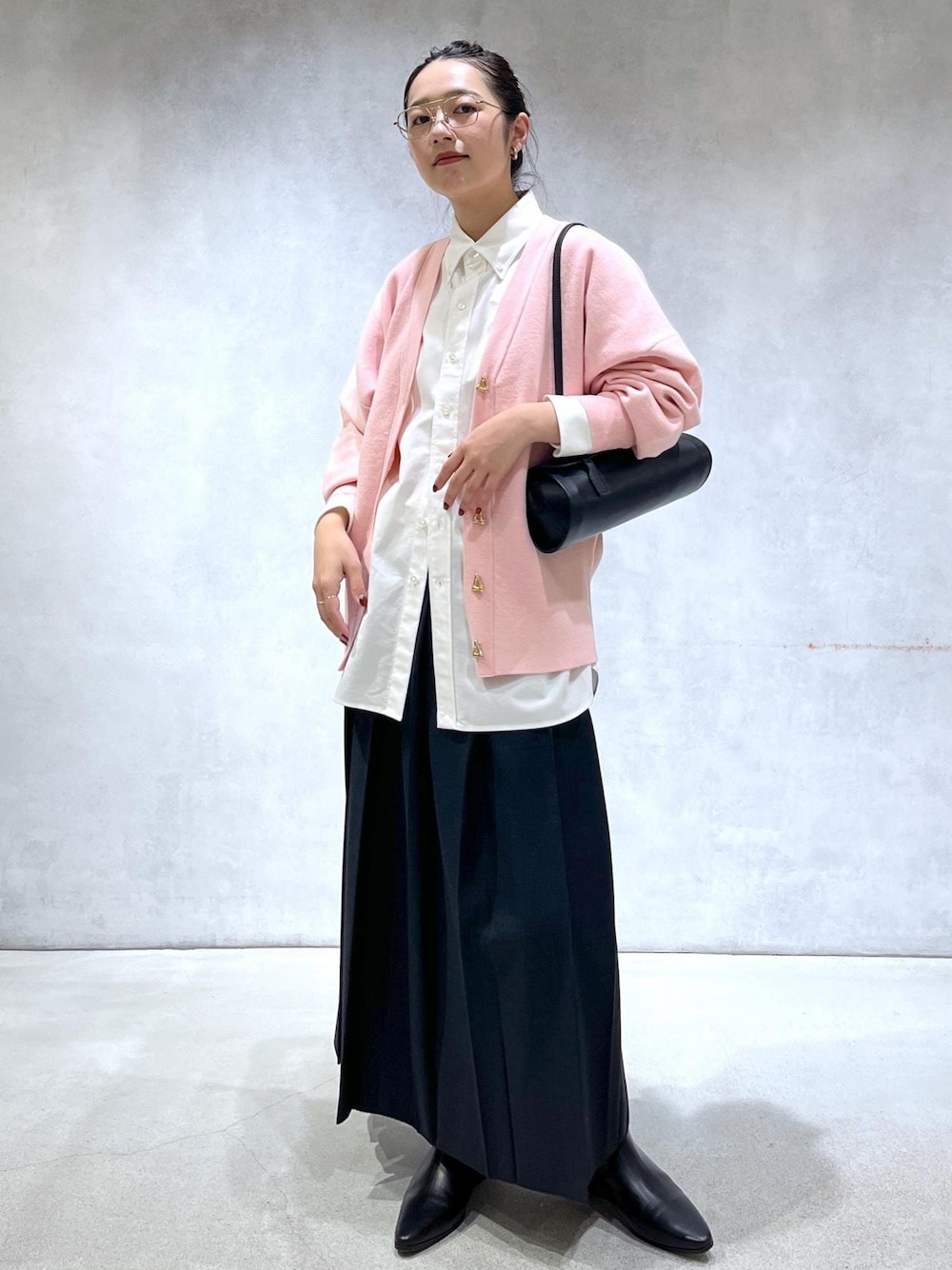 ブラック系のショルダーバッグ、ブラック系のブーツ、ピンク系のカーディガン/ボレロを着用したレディースの秋コーディネートの1枚目の写真