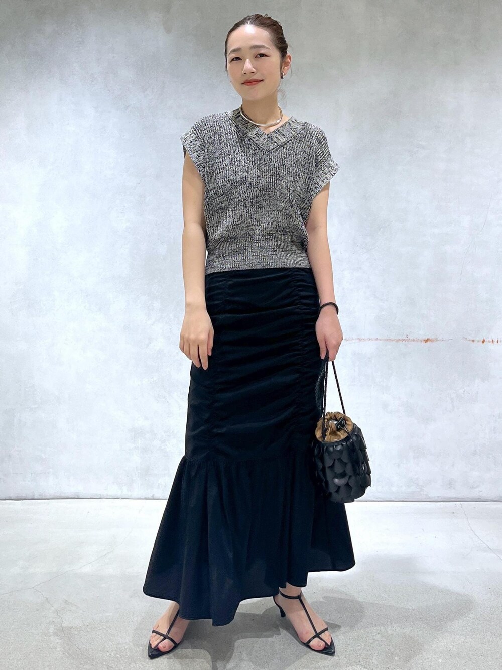 ブラック系のサンダル、ブラック系のスカート、ブラック系のベストを着用したレディースの春コーディネートの1枚目の写真