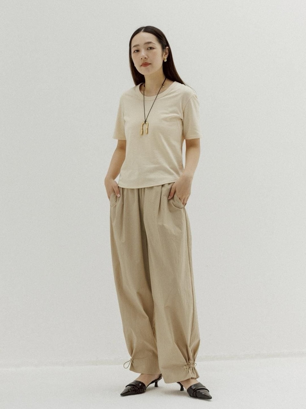 ブラック系のサンダル、ベージュ系のその他パンツ、ベージュ系のTシャツ/カットソーを着用したレディースの春コーディネートの1枚目の写真