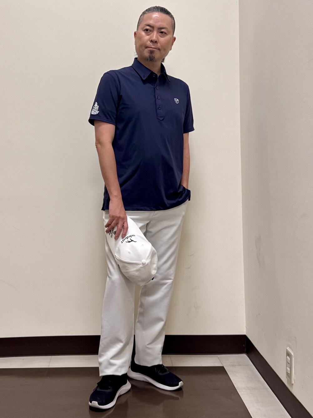 ブルー系のポロシャツ、グレー系のその他パンツ、ホワイト系のキャップを着用したメンズの夏コーディネートの1枚目の写真