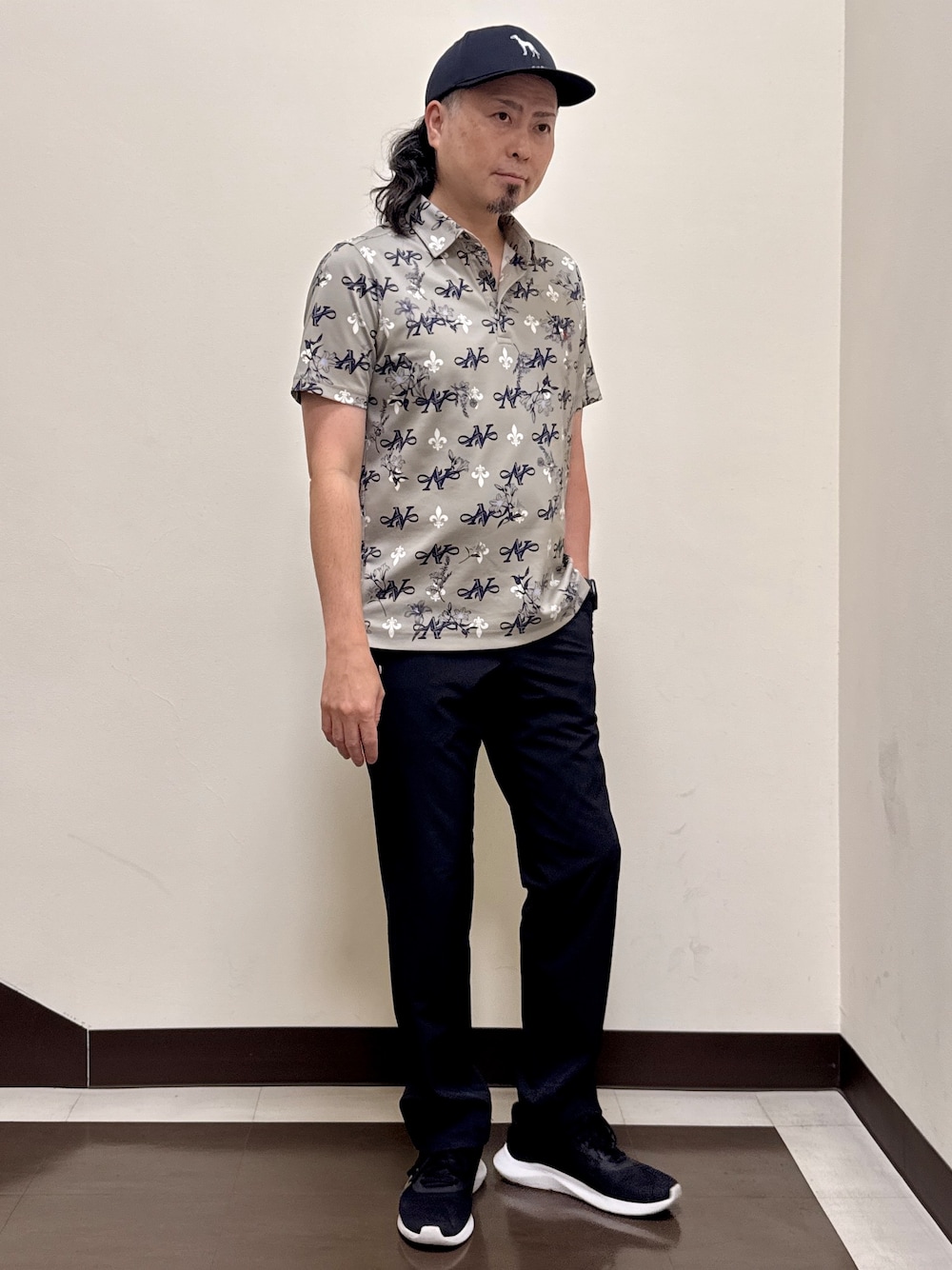 ベージュ系のポロシャツ、ブラック系のその他パンツ、ブラック系のキャップを着用したメンズの夏コーディネートの1枚目の写真