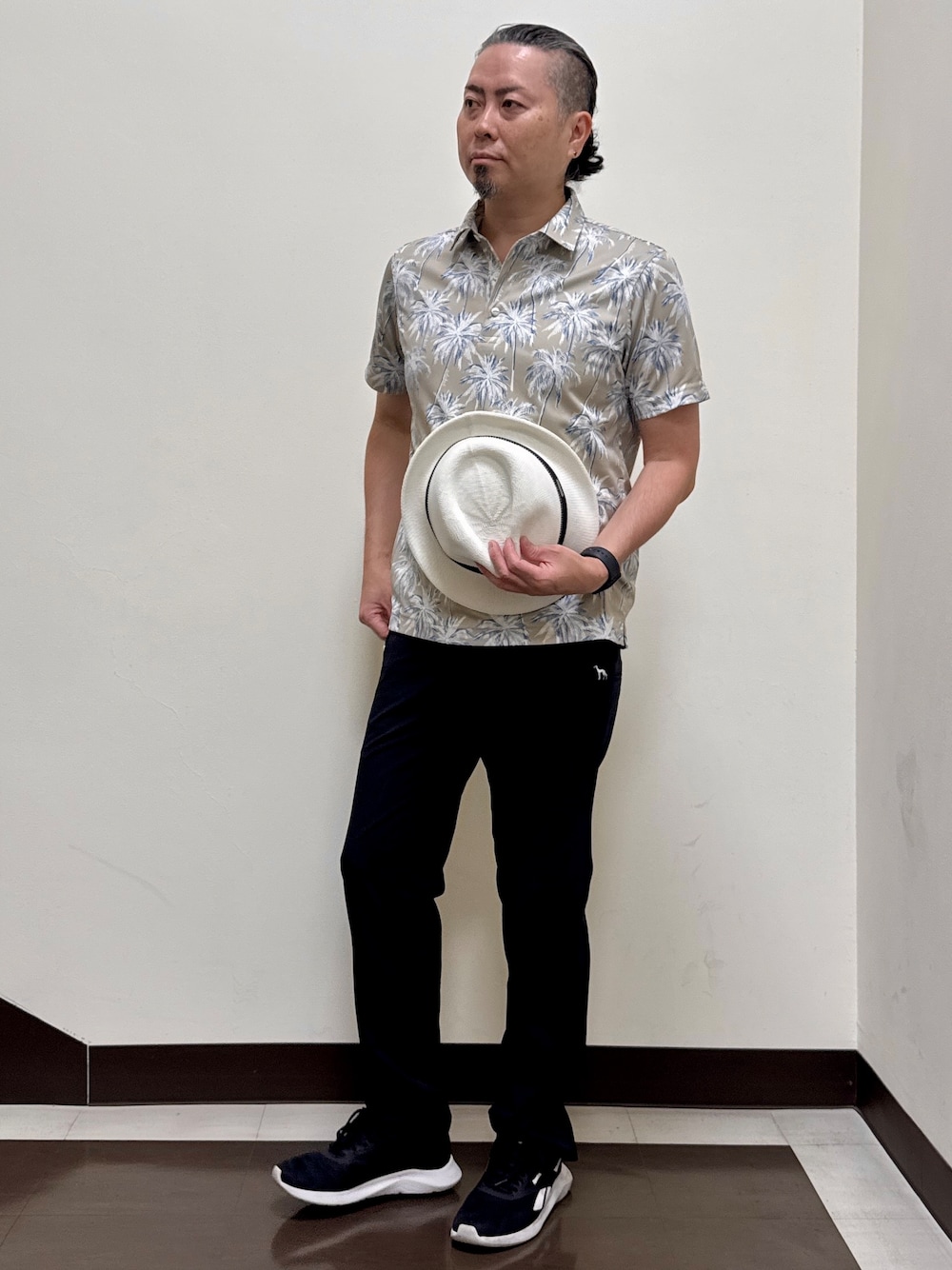 ベージュ系のポロシャツ、ブラック系のその他パンツ、ブラック系のキャップを着用したメンズの夏コーディネートの1枚目の写真