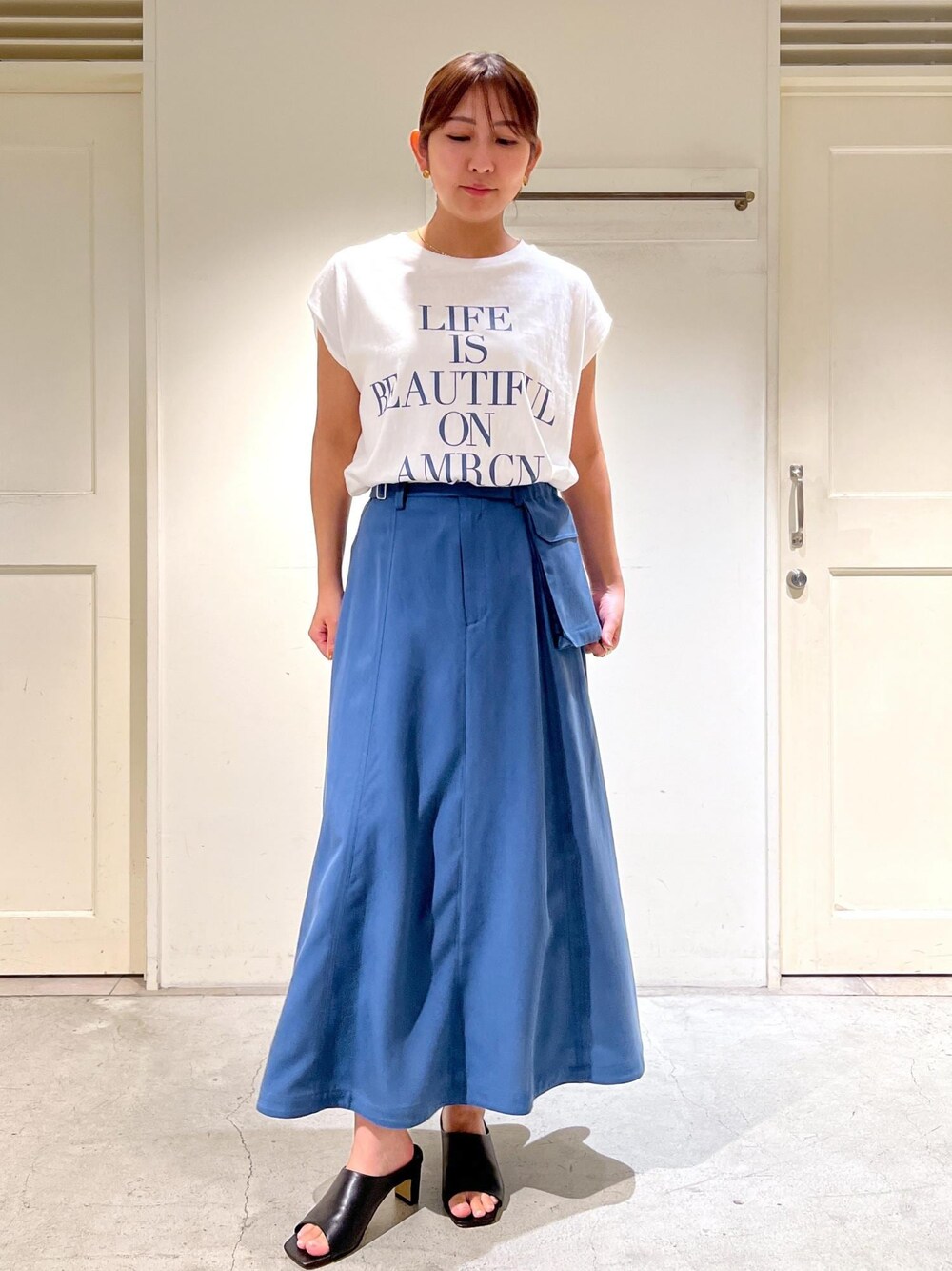 ホワイト系のTシャツ/カットソー、ブルー系のスカート、ブラック系のサンダルを着用したレディースの夏コーディネートの1枚目の写真