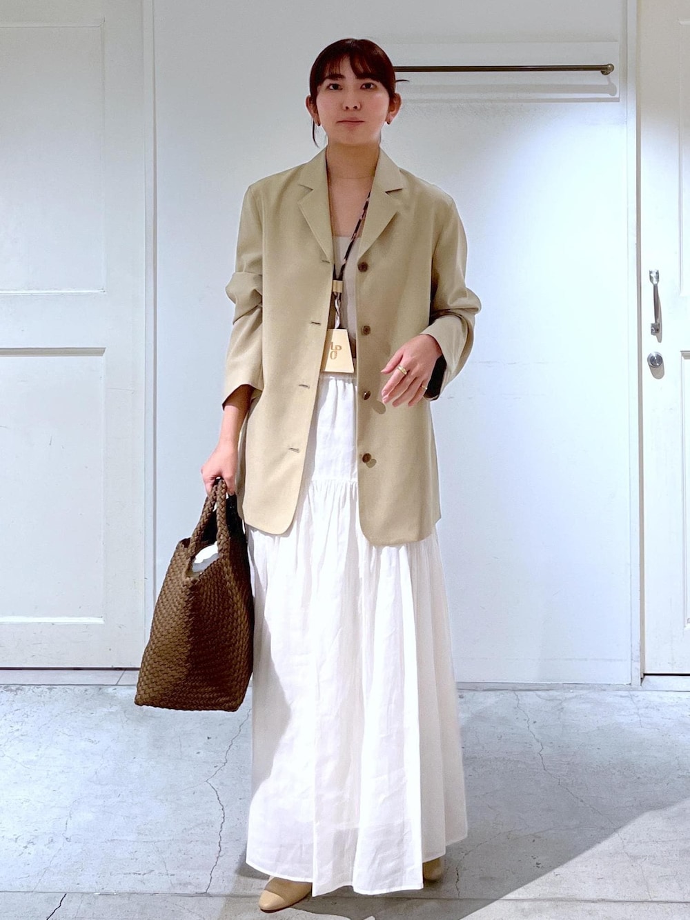 ベージュ系のパンプス、ベージュ系のテーラードジャケット、ホワイト系のスカートを着用したレディースの春コーディネートの1枚目の写真