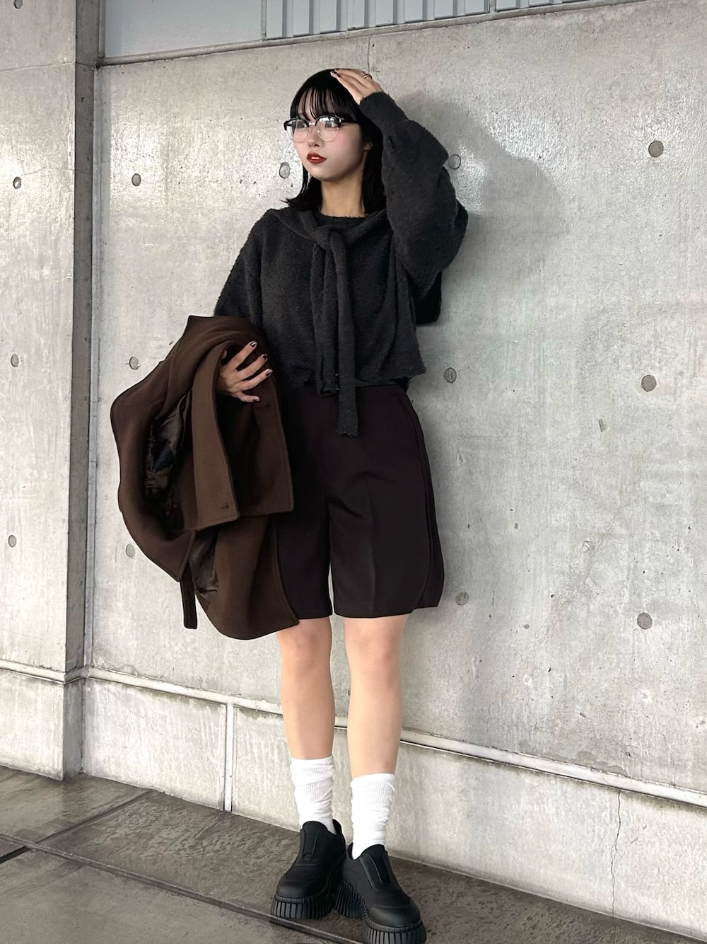 グレー系のニット/セーター、ブラウン系のその他パンツ、ブラック系のスニーカーを着用したレディースの秋コーディネートの1枚目の写真