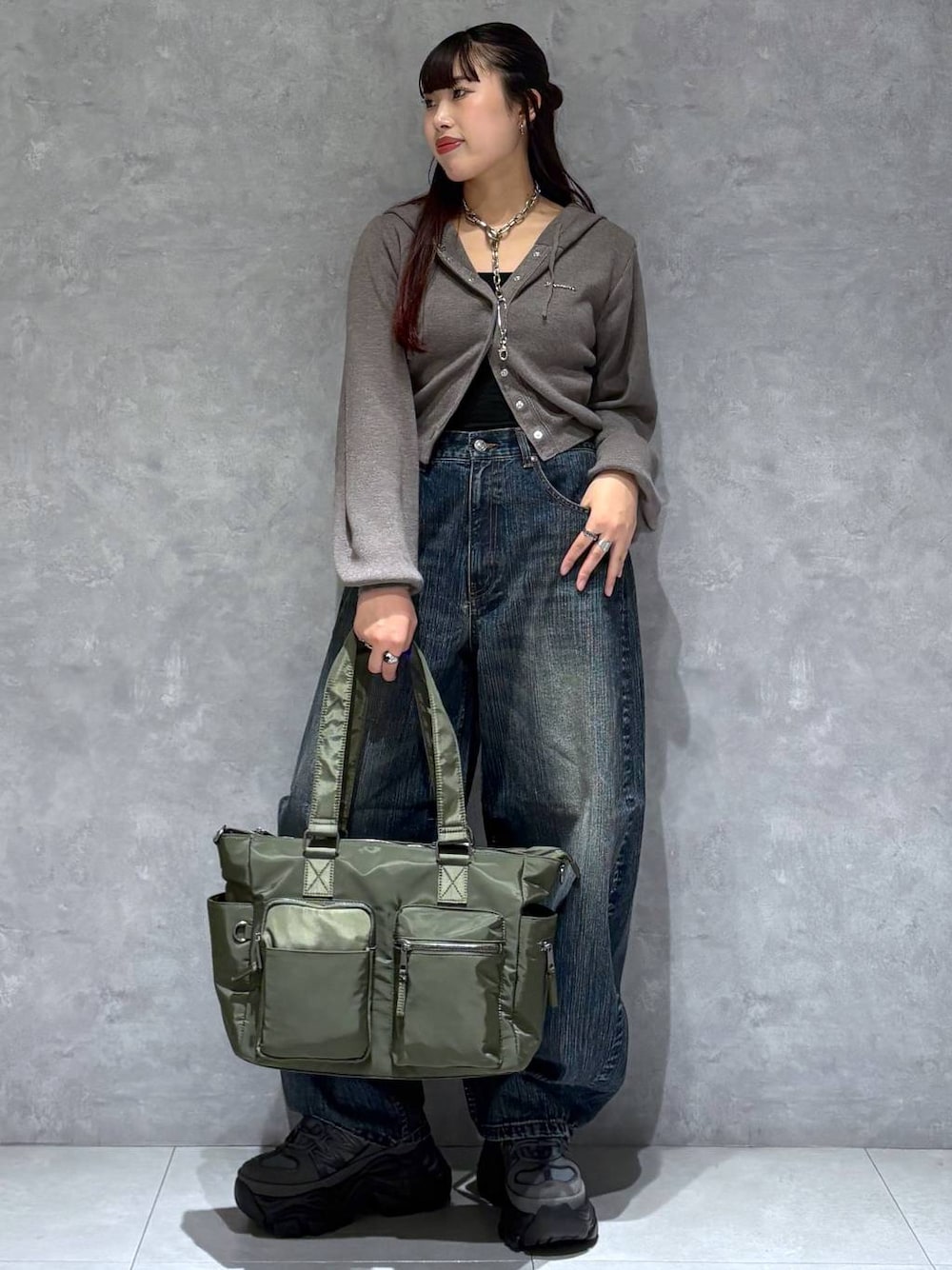 グレー系のスニーカー、グリーン系のボストンバッグ、ブルー系のデニムパンツを着用したレディースの秋コーディネートの1枚目の写真