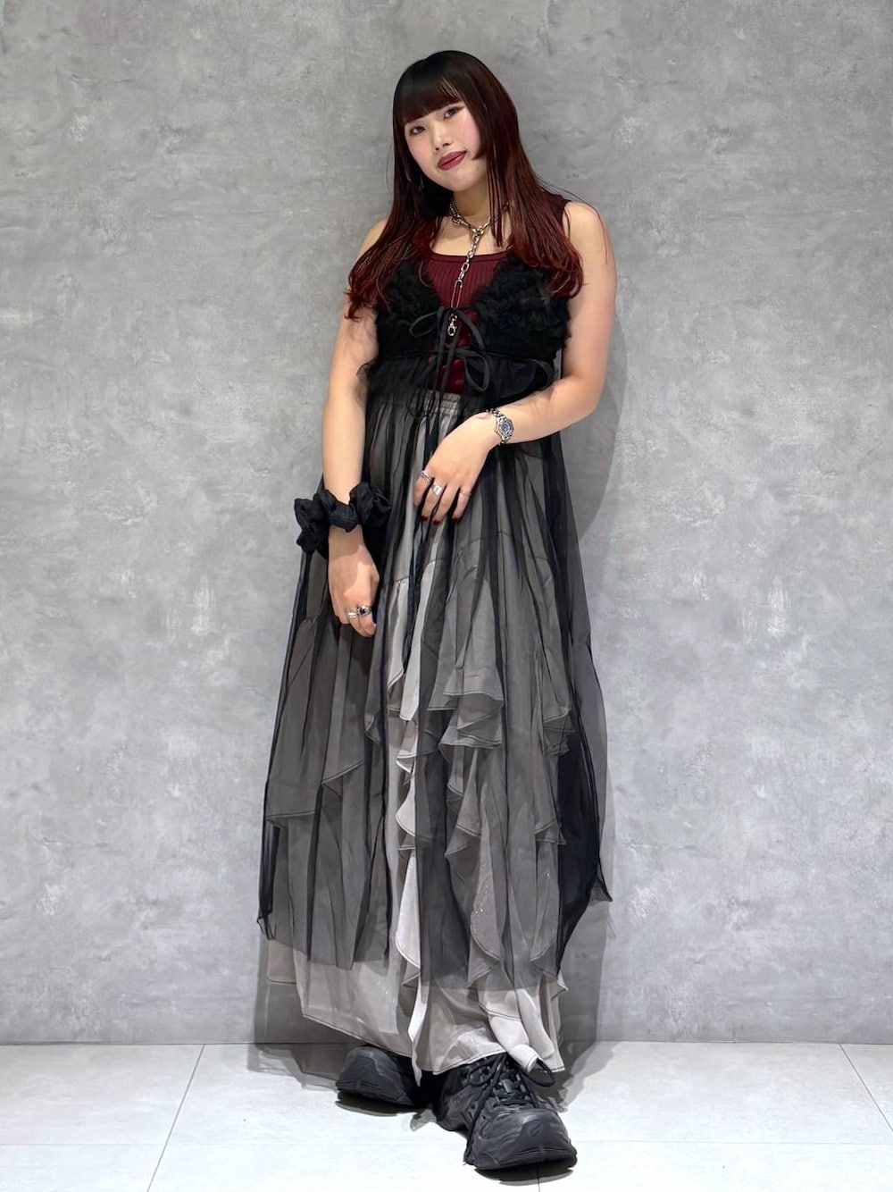 グレー系のスカート、レッド系のタンクトップ、ブラック系のワンピースを着用したレディースの夏コーディネートの1枚目の写真