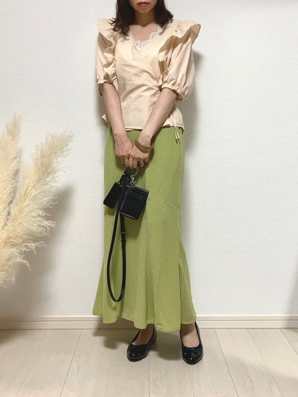 グリーン系のスカート、ブラック系のパンプス、ブラック系のショルダーバッグを着用したレディースの秋コーディネートの1枚目の写真