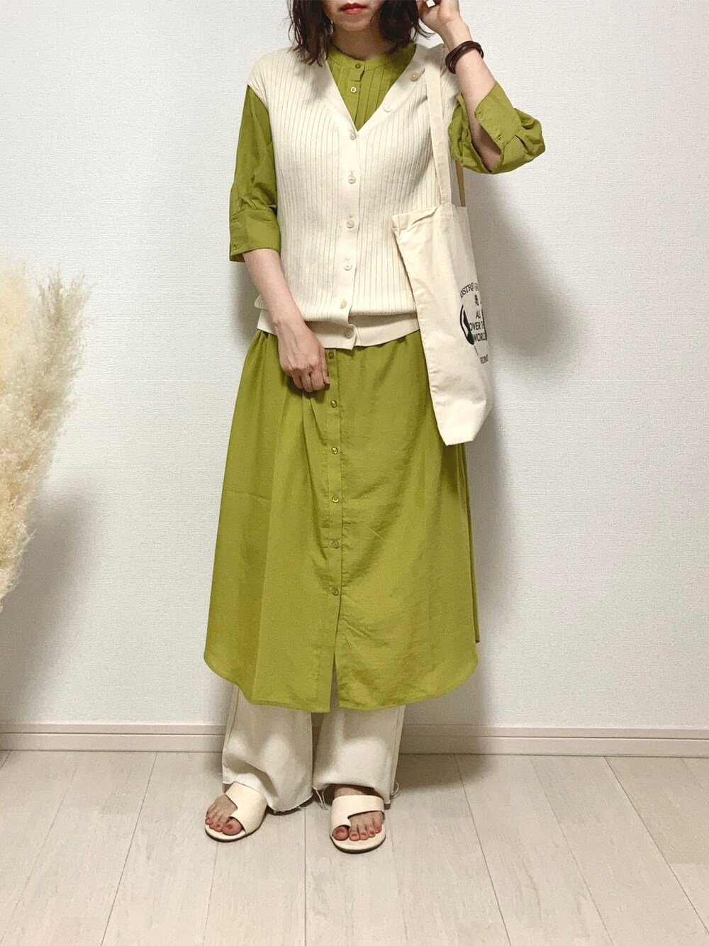 グリーン系のシャツワンピース、ベージュ系のトップス、ホワイト系のデニムパンツを着用したレディースの夏コーディネートの1枚目の写真