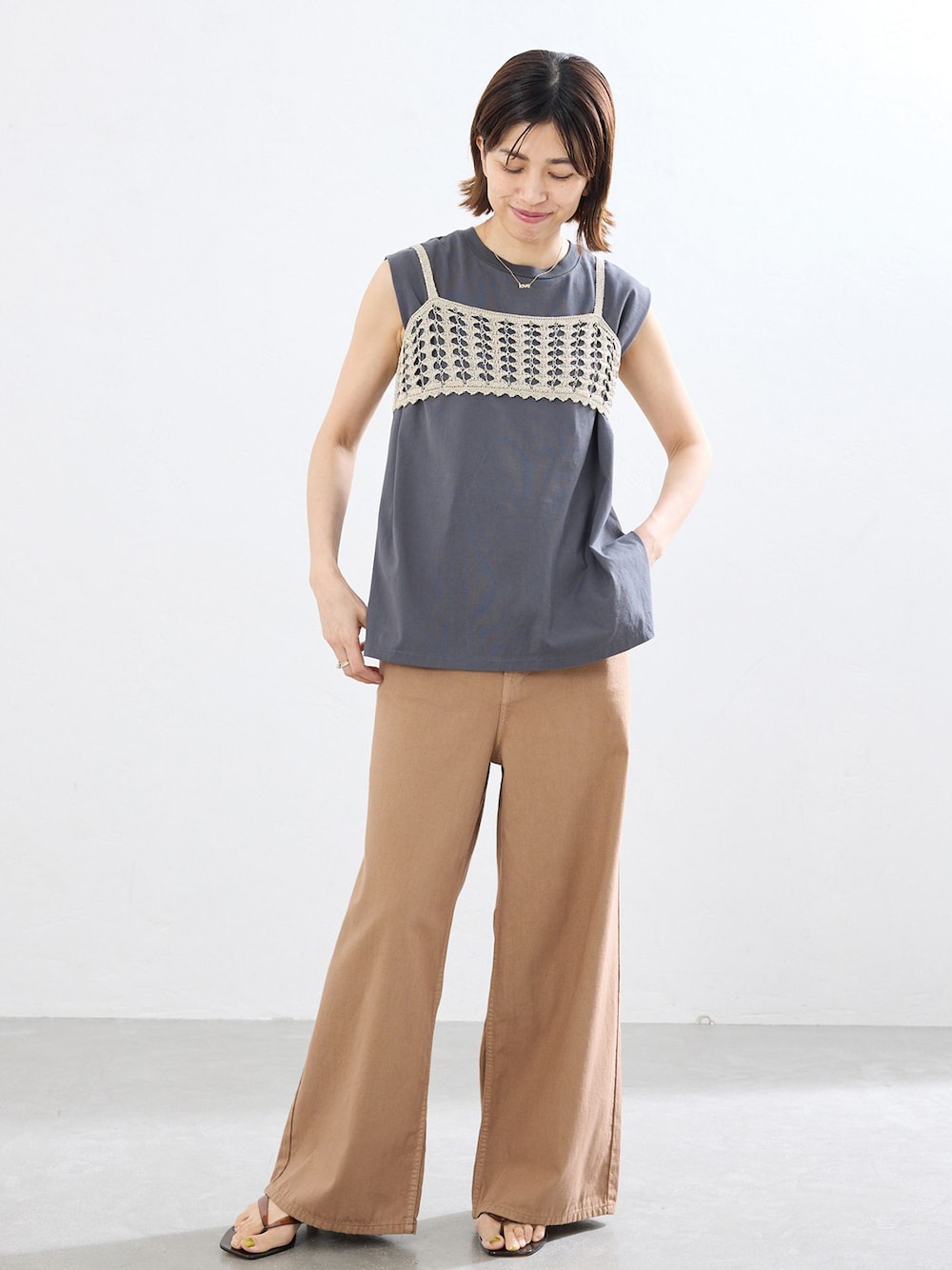 イエロー系のチノパンツ、グレー系のTシャツ/カットソー、ブラウン系のサンダルを着用したレディースの春コーディネートの1枚目の写真