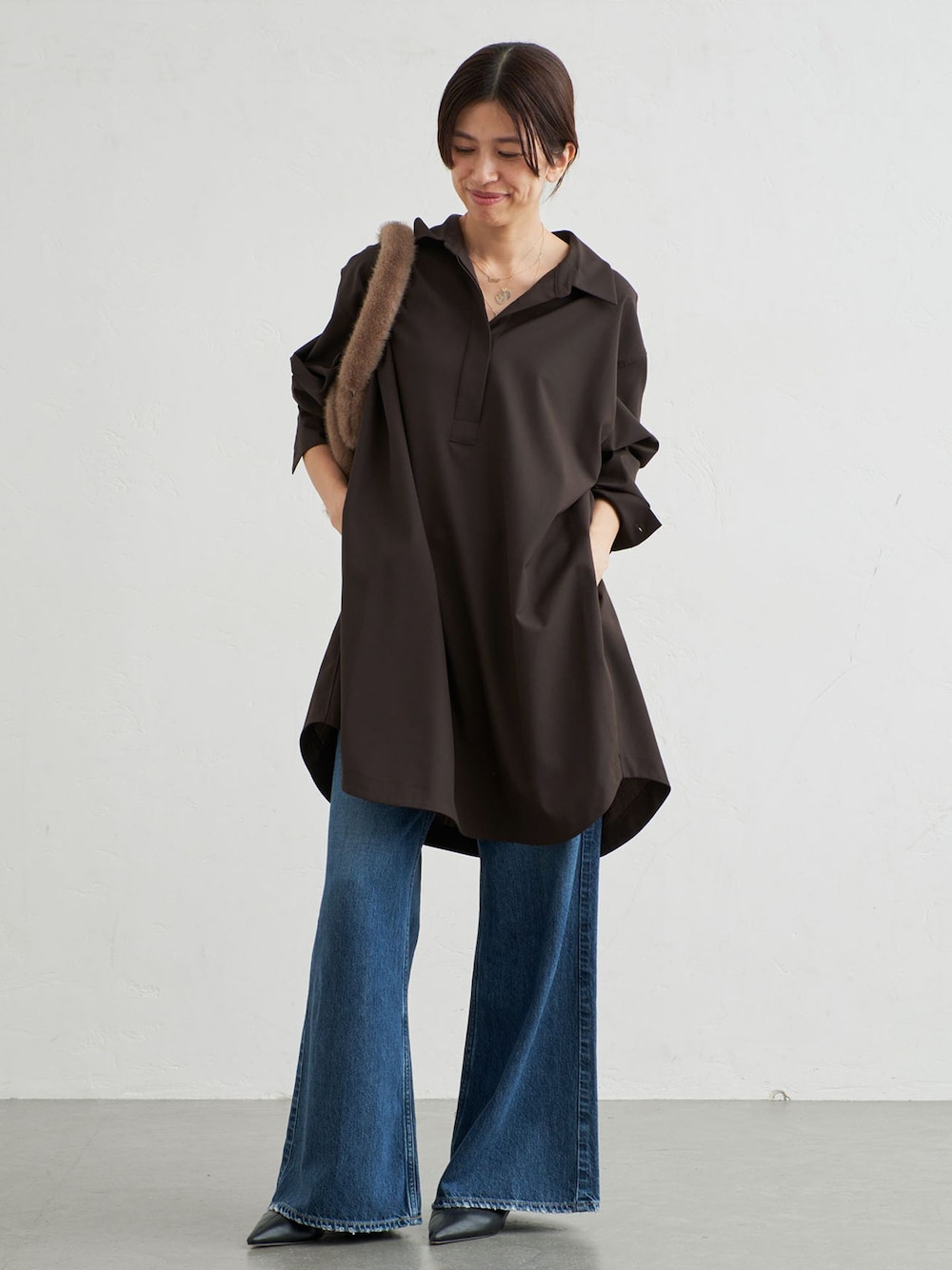 ブルー系のデニムパンツ、ブラウン系のワンピースを着用したレディースの秋コーディネートの1枚目の写真