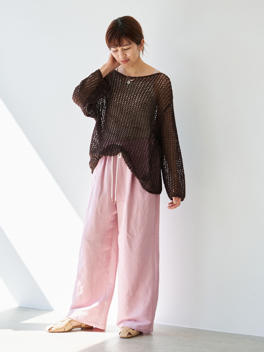 ピンク系のその他パンツ、ブラウン系のニット/セーター、ベージュ系のサンダルを着用したレディースの春コーディネートの1枚目の写真
