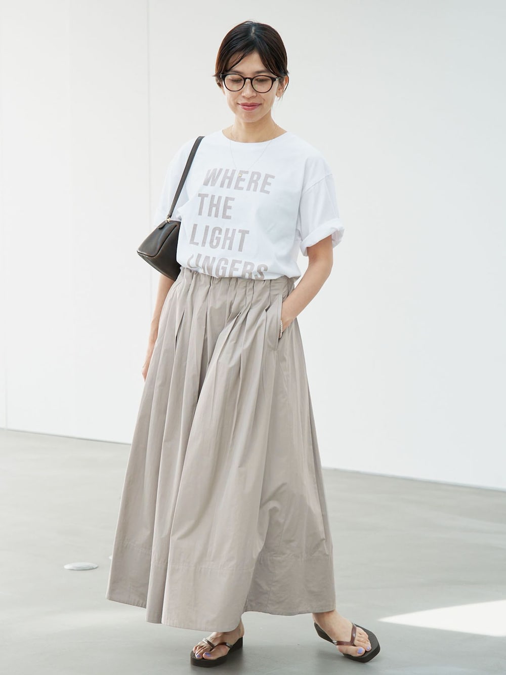 ベージュ系のスカート、ホワイト系のTシャツ/カットソーを着用したレディースの夏コーディネートの1枚目の写真