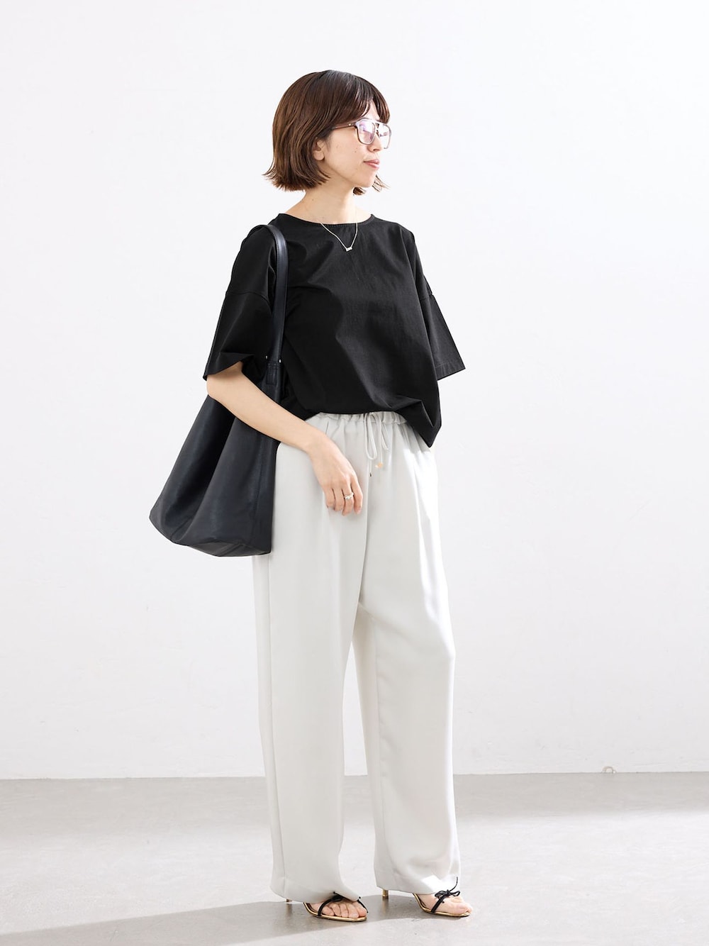 ベージュ系のその他パンツ、ブラック系のTシャツ/カットソー、ブラック系のショルダーバッグを着用したレディースの春コーディネートの1枚目の写真