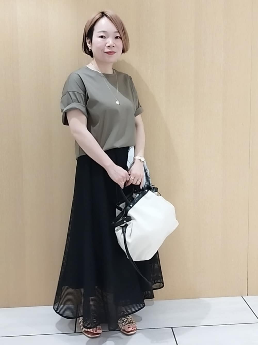 グリーン系のTシャツ/カットソー、ブラック系のスカートを着用したレディースの春コーディネートの1枚目の写真