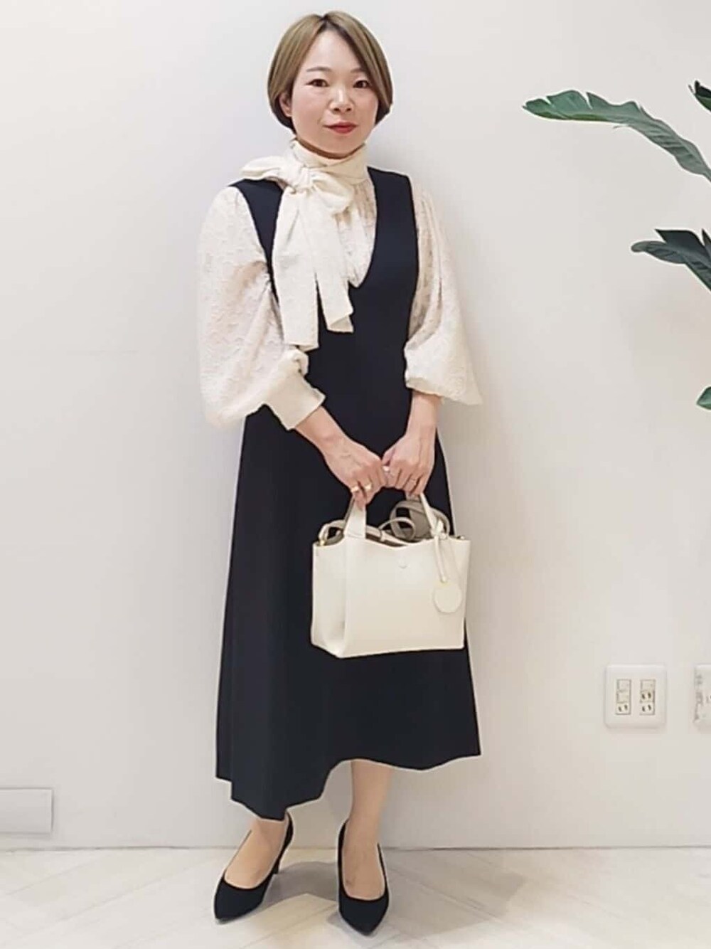 ブラック系のワンピース、ホワイト系のシャツ/ブラウス、ホワイト系のショルダーバッグを着用したレディースの冬コーディネートの1枚目の写真