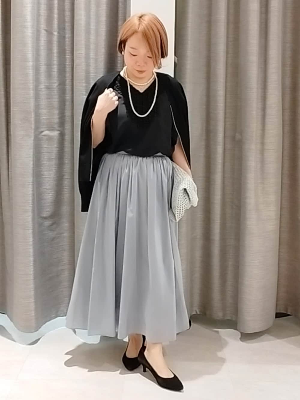 ブルー系のスカート、ブラック系のカーディガン/ボレロ、シルバー系のトートバッグを着用したレディースの春コーディネートの1枚目の写真
