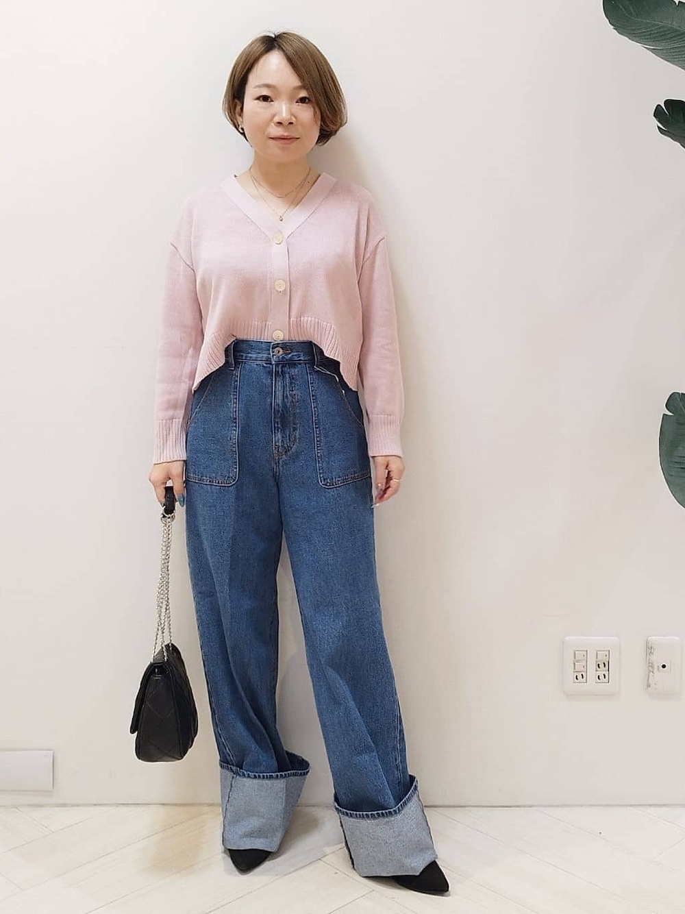 ピンク系のカーディガン/ボレロ、ブルー系のデニムパンツ、ブラック系のショルダーバッグを着用したレディースの冬コーディネートの1枚目の写真