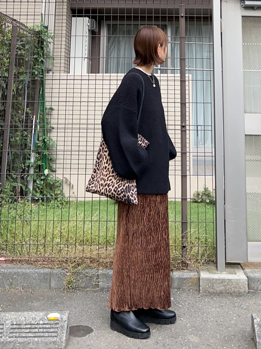 ブラウン系のスカート、ブラウン系のトートバッグ、ブラック系のニット/セーターを着用したレディースの秋コーディネートの1枚目の写真