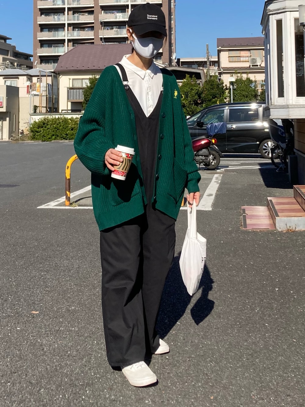 グリーン系のカーディガン/ボレロ、ホワイト系のシャツ/ブラウス、ブラック系のサロペット/オーバーオールを着用したレディースの秋コーディネートの1枚目の写真