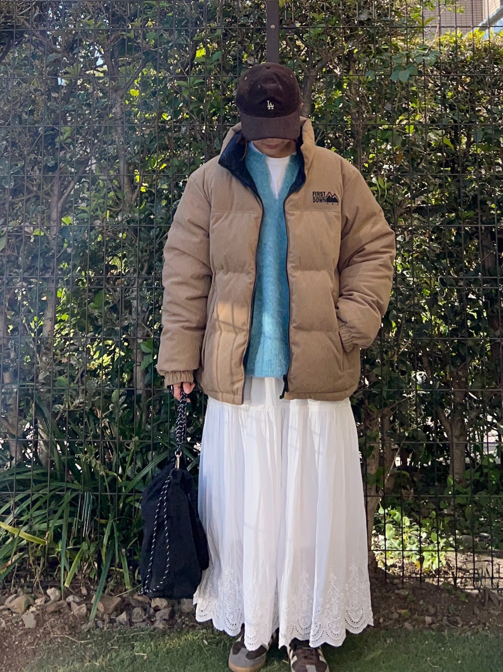 ブルー系のニット/セーター、ベージュ系のダウンジャケット/コート、ホワイト系のスカートを着用したレディースの冬コーディネートの1枚目の写真