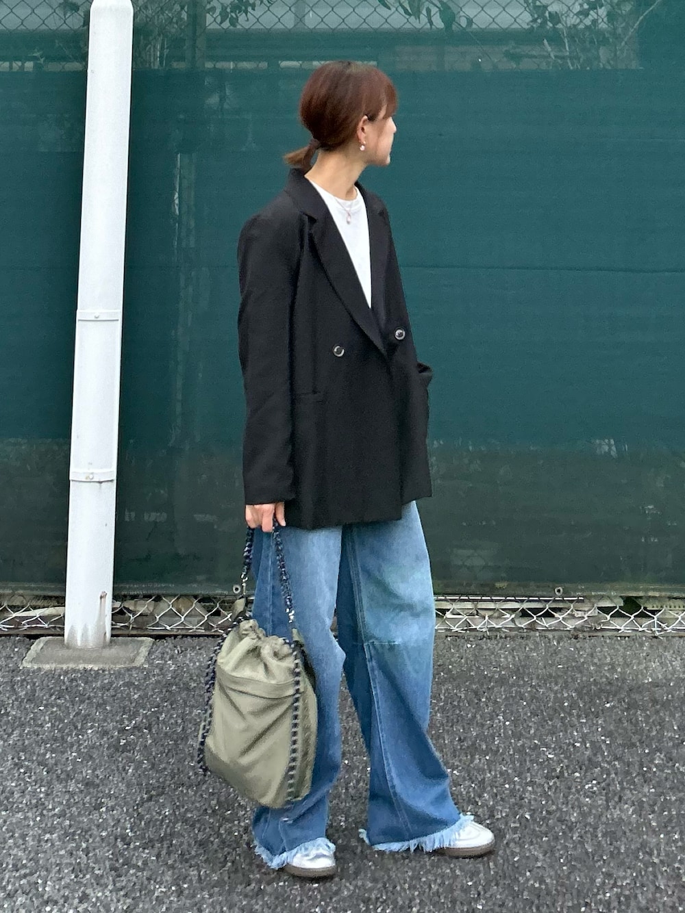ブラック系のテーラードジャケット、ブルー系のデニムパンツ、グリーン系のトートバッグを着用したレディースの秋コーディネートの1枚目の写真