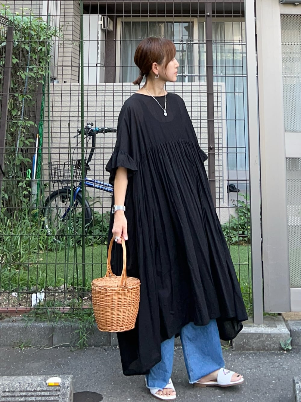ブラック系のワンピース、ブルー系のデニムパンツ、ホワイト系のサンダルを着用したレディースの夏コーディネートの1枚目の写真