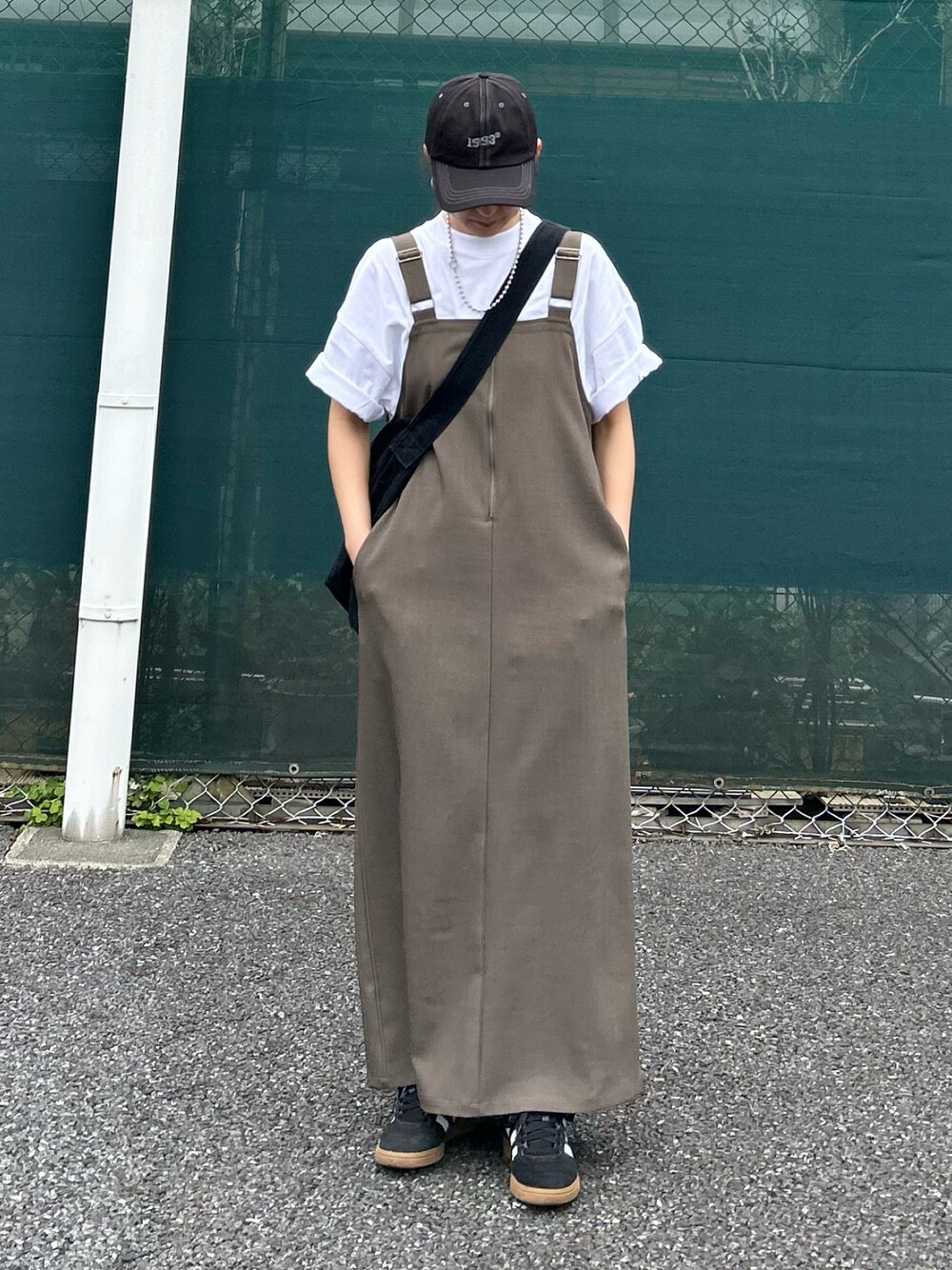 ベージュ系のワンピース、ホワイト系のTシャツ/カットソー、ブラック系のショルダーバッグを着用したレディースの春コーディネートの1枚目の写真