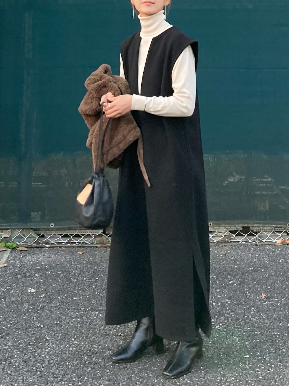 ブラック系のワンピース、ブラック系のハンドバッグ、ブラック系のブーツを着用したレディースの冬コーディネートの1枚目の写真