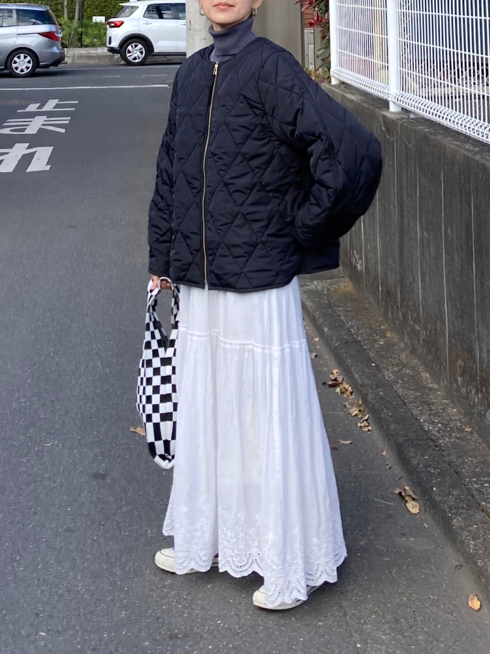 ブラック系のその他アウター、グレー系のニット/セーター、ホワイト系のスカートを着用したレディースの秋コーディネートの1枚目の写真