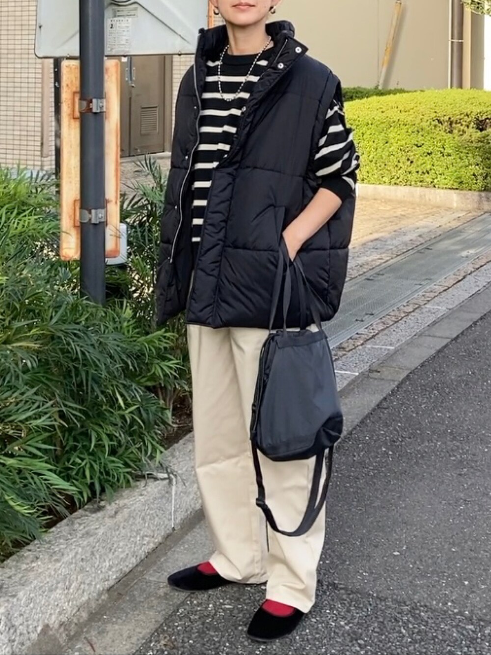 ブラック系のダウンベスト、ベージュ系のチノパンツ、ブラック系のニット/セーターを着用したレディースの秋コーディネートの1枚目の写真