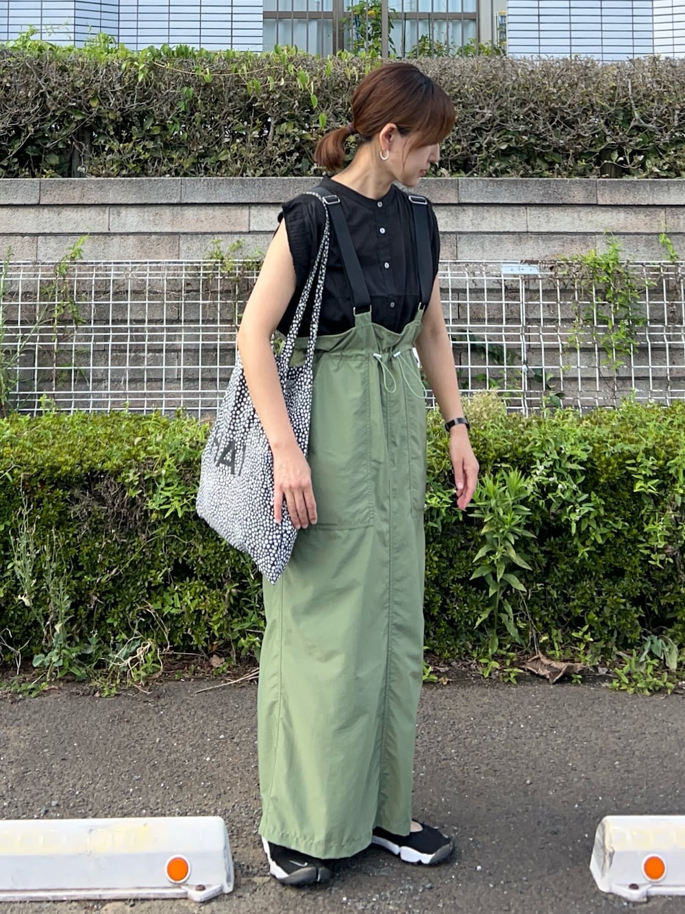 ブラック系のシャツ/ブラウス、グリーン系のジャンパースカート、ブラック系のスニーカーを着用したレディースの夏コーディネートの1枚目の写真
