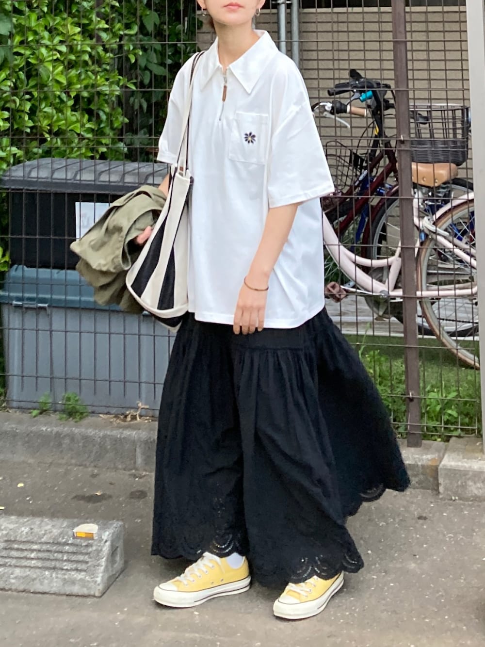 ブラック系のスカート、ブラック系のトートバッグ、イエロー系のスニーカーを着用したレディースの春コーディネートの1枚目の写真