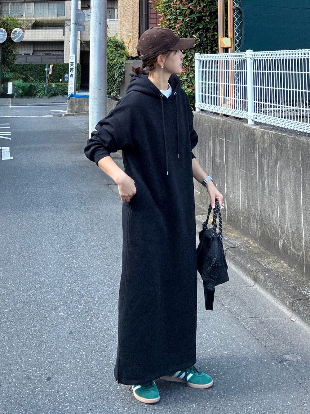 ブラック系のワンピース、ブラック系のトートバッグ、グリーン系のスニーカーを着用したレディースの夏コーディネートの1枚目の写真