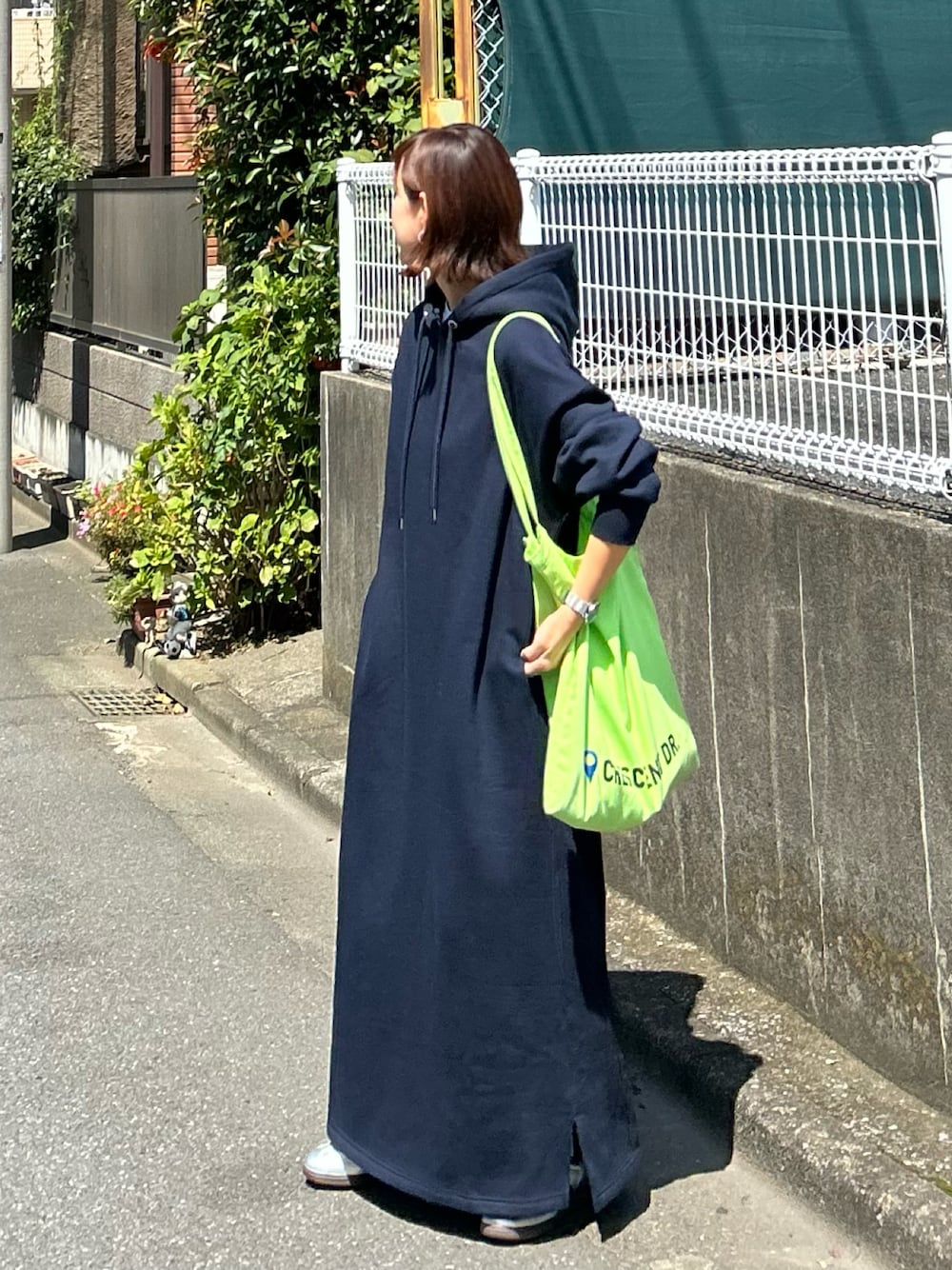 ブルー系のワンピース、グリーン系のトートバッグ、シルバー系のスニーカーを着用したレディースの秋コーディネートの1枚目の写真