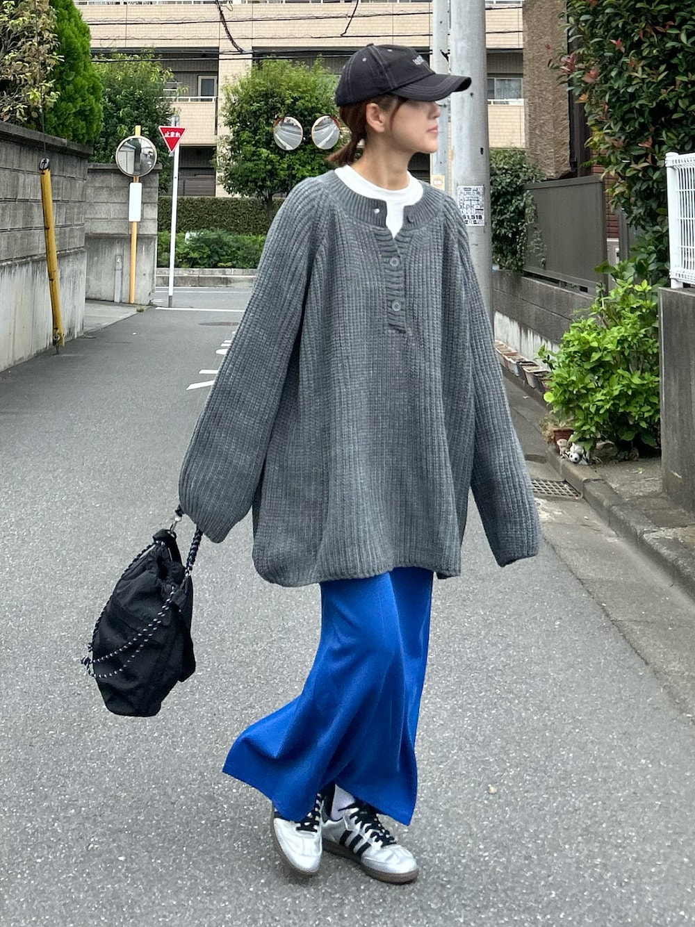 グレー系のニット/セーター、ブラック系のショルダーバッグ、ブルー系のスカートを着用したレディースの秋コーディネートの1枚目の写真
