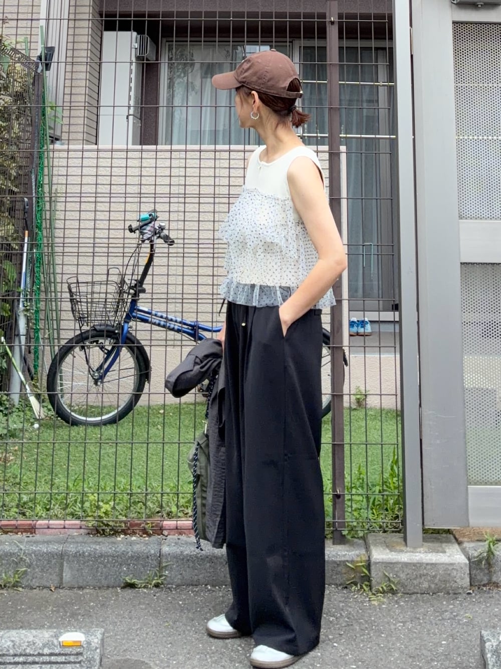 ホワイト系のニット/セーター、ブラック系のスラックス、シルバー系のスニーカーを着用したレディースの夏コーディネートの1枚目の写真