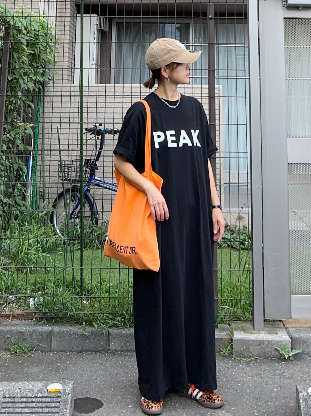 ブラック系のワンピース、オレンジ系のトートバッグ、ブラック系のスニーカーを着用したレディースの夏コーディネートの1枚目の写真