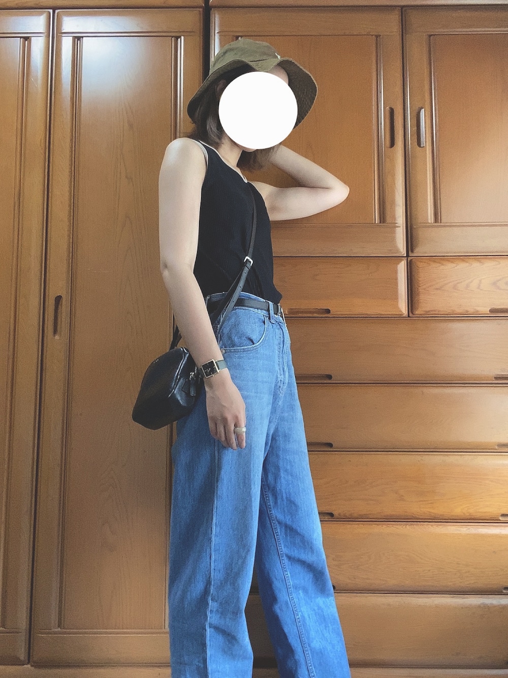 ブラック系のショルダーバッグ、ブルー系のデニムパンツ、ブラック系のサンダルを着用したレディースの夏コーディネートの1枚目の写真