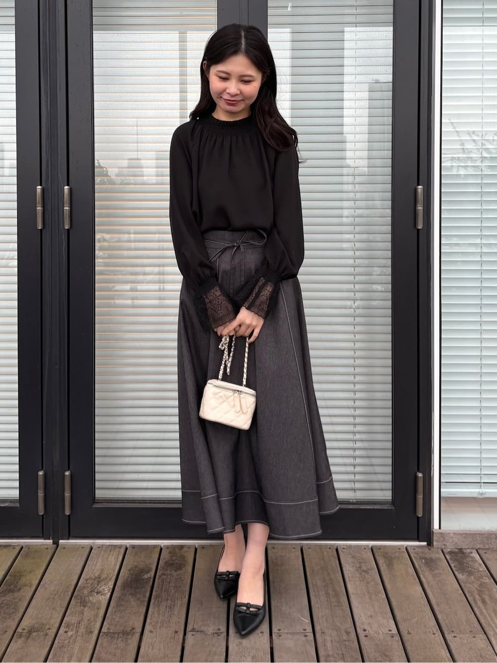 ブラック系のシャツ/ブラウス、ブラック系のスカート、ブラック系のパンプスを着用したレディースの春コーディネートの1枚目の写真