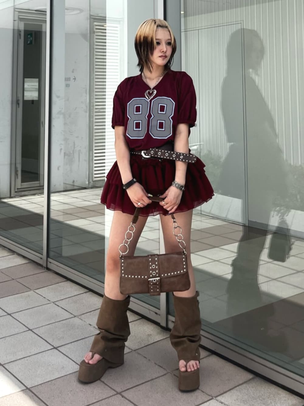 レッド系のワンピース、ブラウン系のハンドバッグ、ブラウン系のサンダルを着用したレディースの春コーディネートの1枚目の写真