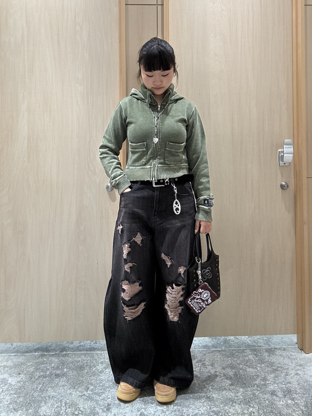 ブラック系のデニムパンツ、グリーン系のパーカー、ブラック系のショルダーバッグを着用したレディースの秋コーディネートの1枚目の写真