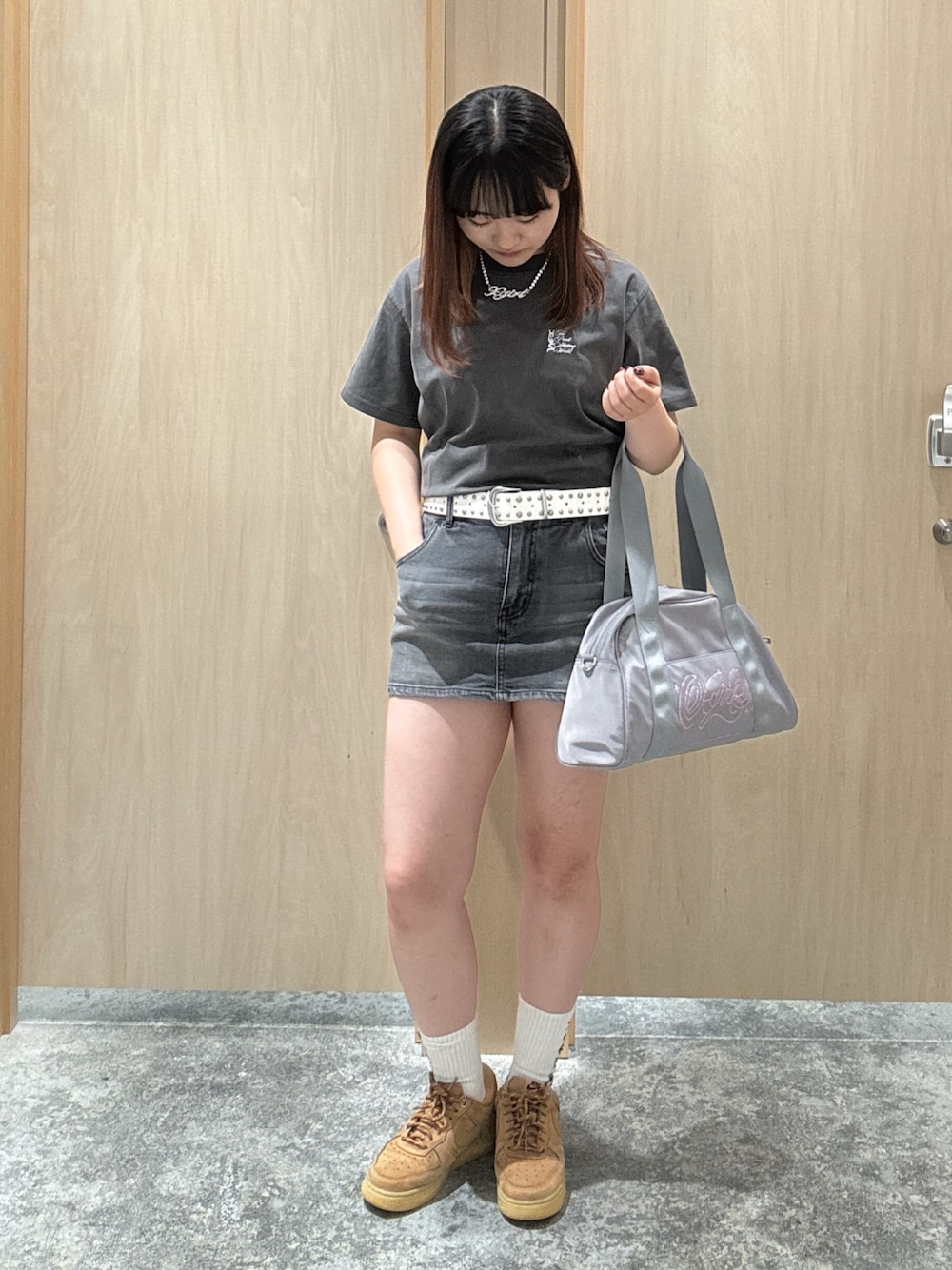 ブラック系のデニムスカート、ブラック系のTシャツ/カットソー、グレー系のハンドバッグを着用したレディースの夏コーディネートの1枚目の写真