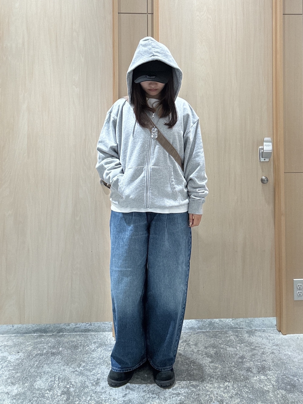 グレー系のパーカー、ホワイト系のTシャツ/カットソー、ブルー系のデニムパンツを着用したレディースの秋コーディネートの1枚目の写真