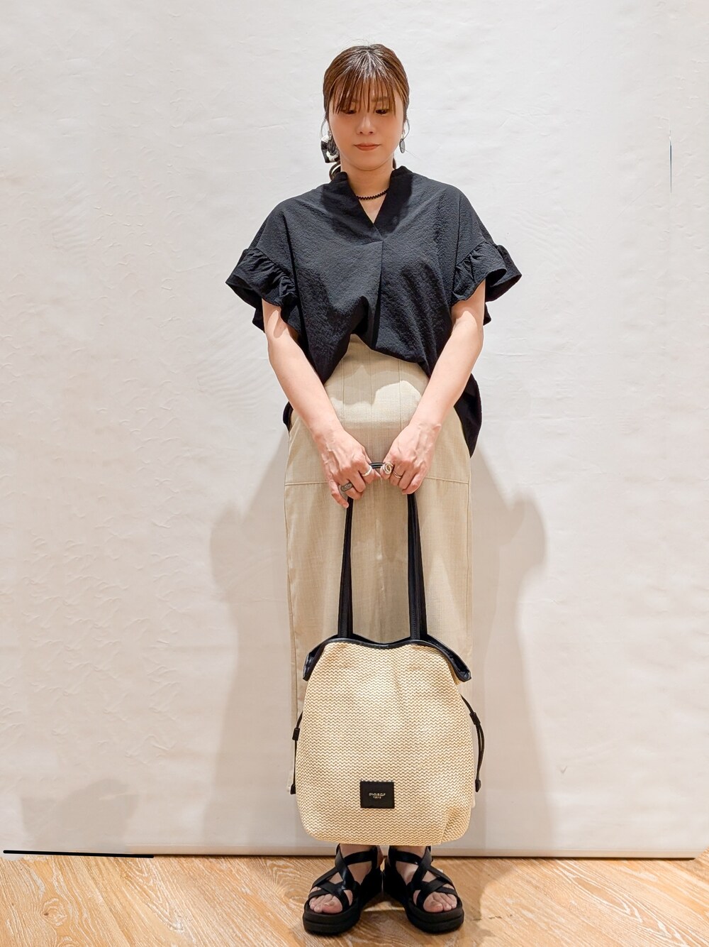 ブラック系のシャツ/ブラウス、ベージュ系のスカート、ホワイト系のトートバッグを着用したレディースの春コーディネートの1枚目の写真