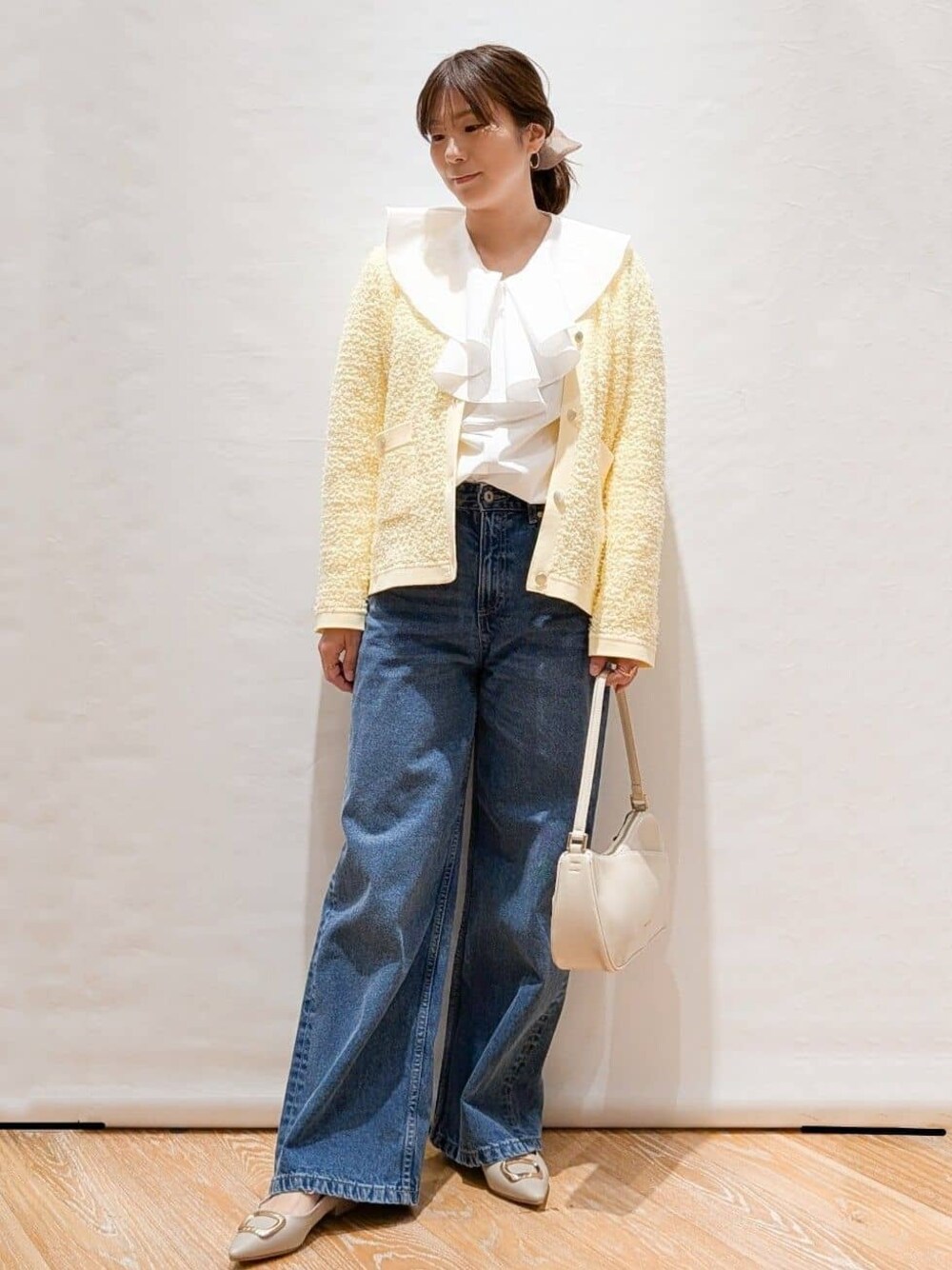 イエロー系のカーディガン/ボレロ、ホワイト系のシャツ/ブラウス、ブルー系のデニムパンツを着用したレディースの冬コーディネートの1枚目の写真