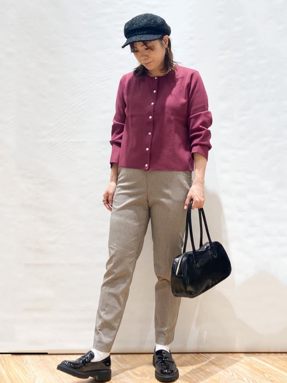 レッド系のカーディガン/ボレロ、ブラウン系のその他パンツ、ブラック系のボストンバッグを着用したレディースの秋コーディネートの1枚目の写真