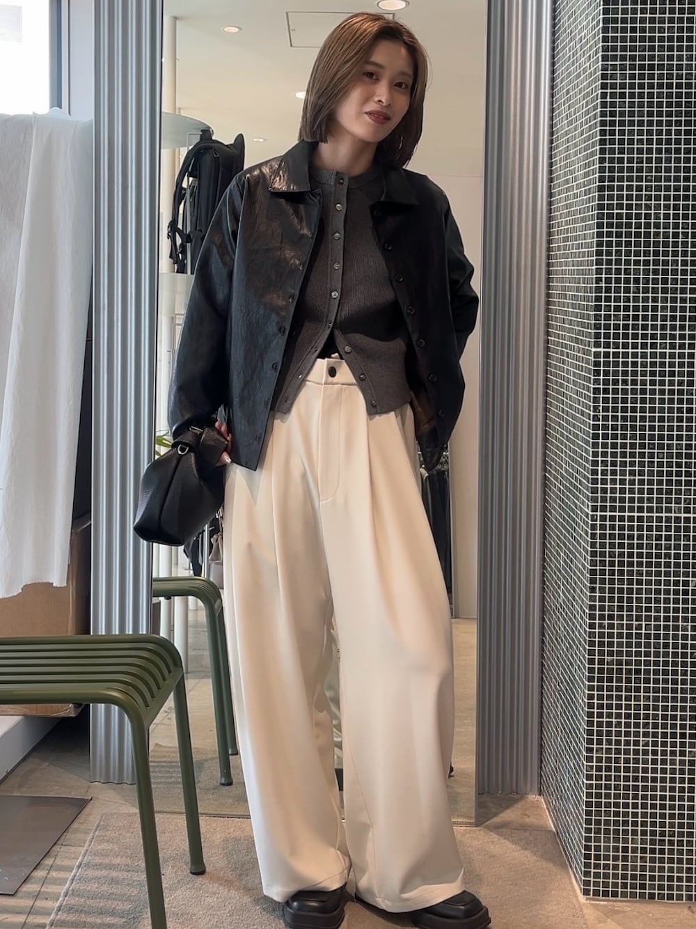 グレー系のスラックス、ブラック系のトートバッグ、グレー系のカーディガン/ボレロを着用したレディースの春コーディネートの1枚目の写真